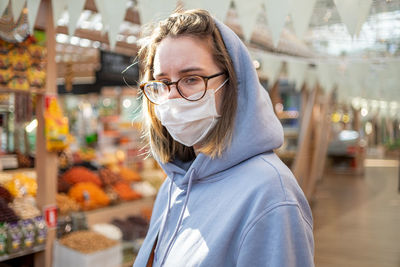 Portrait of young woman standing against store