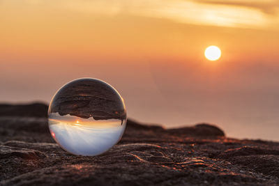 Close-up of crystal ball on rock at beach during sunset