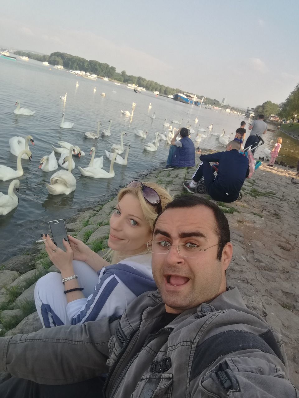 YOUNG MAN AND WOMAN USING SMART PHONE ON BEACH