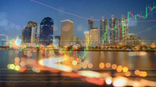 Digital composite image of graph with illuminated buildings in city at night