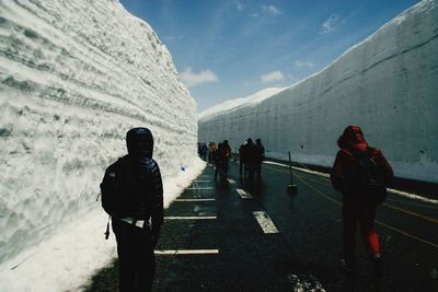 Rear view of people walking on snow covered mountain