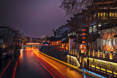 Light trails on street amidst buildings at night