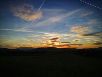 Scenic view of silhouette field against sky at sunset