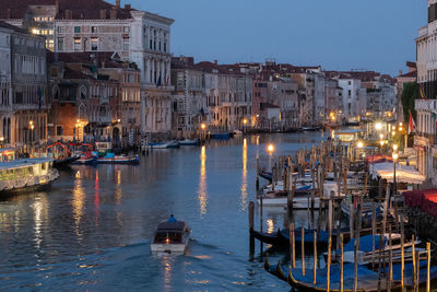 Boats moored in canal by buildings in city