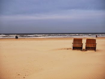 Scenic view of beach against cloudy sky