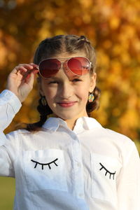 Portrait of cute smiling girl wearing sunglasses in park during autumn