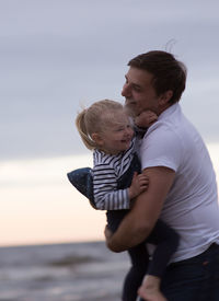 Father and daughter playing at beach against sky