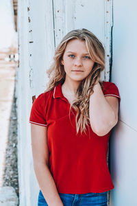 Portrait of beautiful young woman standing against wall