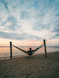 Rear view of person on beach against sky during sunset