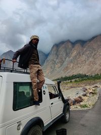 Side view of man on car against mountain range