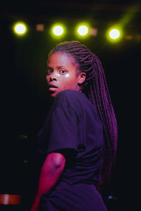 Portrait of woman dancing against illuminated lights