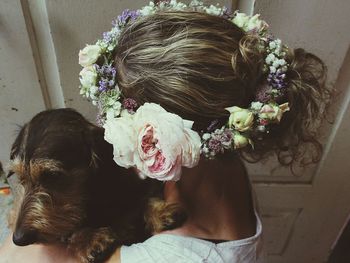 Side view of woman wearing flowers carrying dog