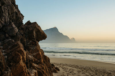 Rocky outcrop and desolate beach. no people and a peaceful beach at sunrise.