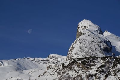 Low angle view of snowcapped mountain against blue sky