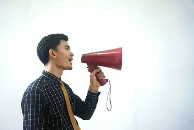 Side view of young man against red background