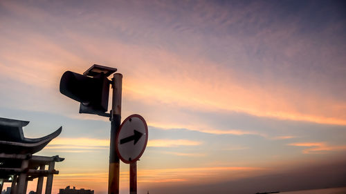 Low angle view of road sign against sky during sunset