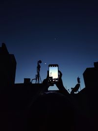 Silhouette people photographing against clear blue sky