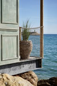 Built structure by sea against sky seen through window