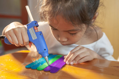 Close-up of girl making craft product on table