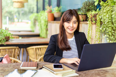 Portrait of a smiling young woman sitting at table