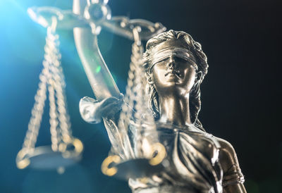 Close-up of lady justice statue against black background