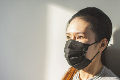 Close-up portrait of young woman against wall