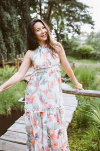 Happy multiracial japanese woman in romantic floral maxi dress in park