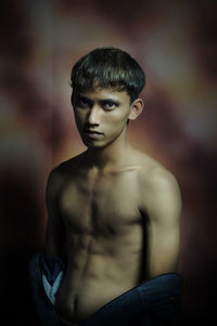 Portrait of young man standing against gray background