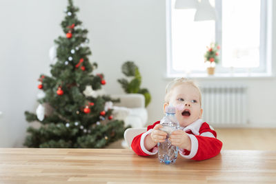 Portrait of cute girl playing with christmas tree at home