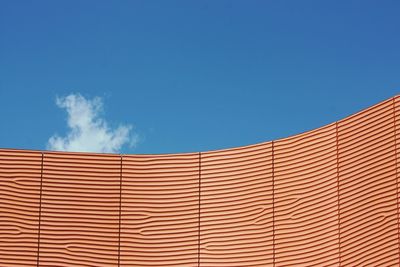 Low angle view of patterned wall against blue sky