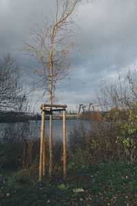Wooden post on lakeshore against sky