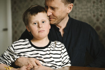Portrait of boy having down syndrome with father at home