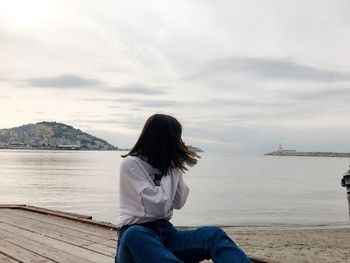 Rear view of woman looking at sea against sky