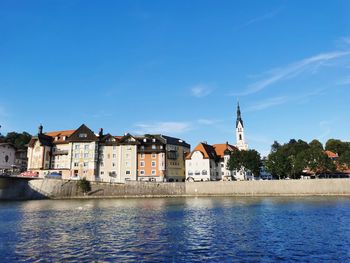 River by buildings against blue sky