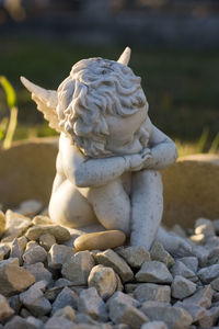 Close-up of angel sculpture on gravels at cemetery