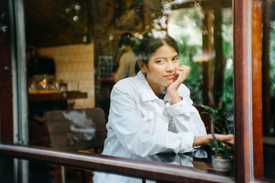 Portrait of woman looking through glass window at cafe