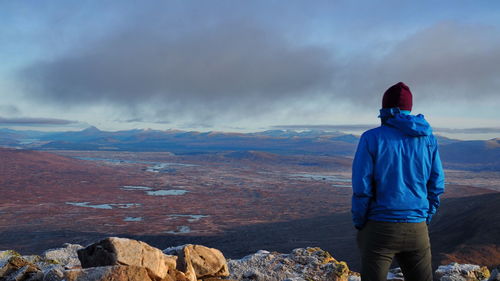 Rear view of man looking at mountain against sky