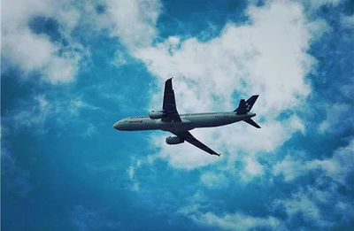 Low angle view of airplane against cloudy sky