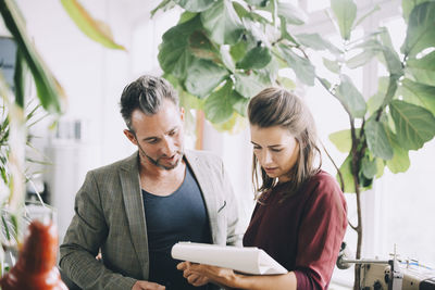 Businessman and businesswoman discussing over note pad in creative office