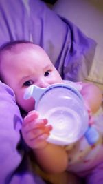 Close-up portrait of baby boy drinking milk while lying on bed at home