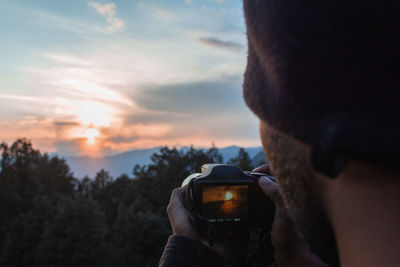 Close-up of man photographing sky during sunset