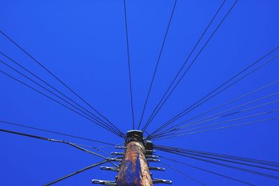 Low angle view of electricity pylon against blue sky