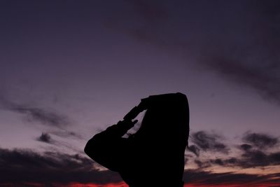 Low angle view of silhouette man using mobile phone against sky