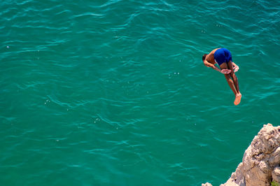 High angle view of shirtless man jumping in sea