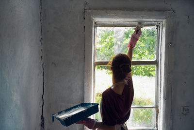 Rear view of woman sitting by window