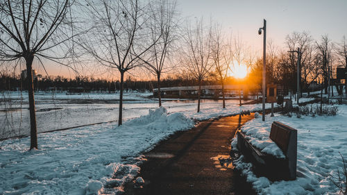 Scenic view of frozen canal against sky during sunset