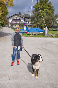 Portrait of woman with dog standing on road