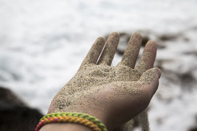 Close-up of hand holding sand at beach