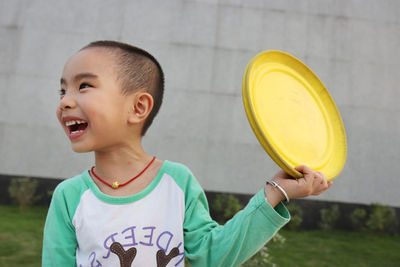 Cheerful boy playing with plastic disc at park