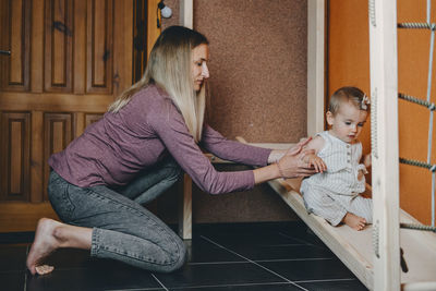 Active games for baby indoors activities. toddler girl play with mom on home wooden playsets. 